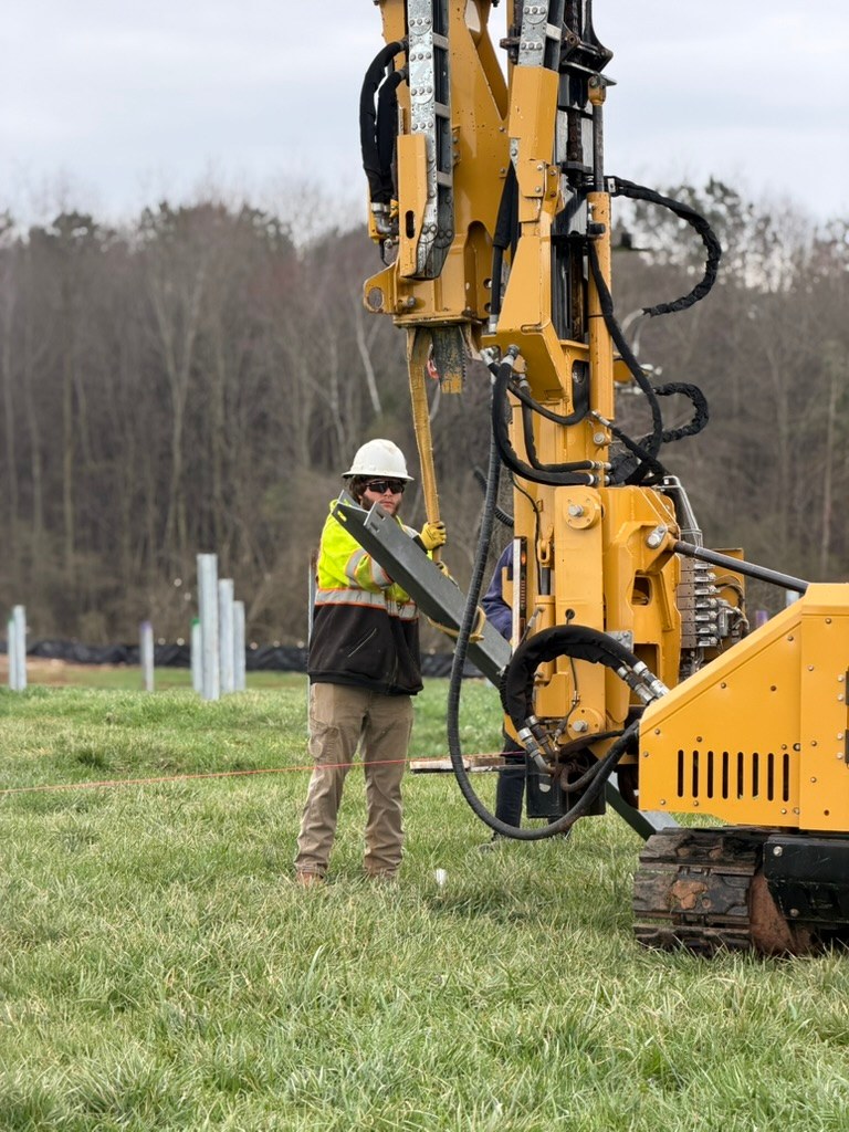 Crew member working beside pile-driving equipment